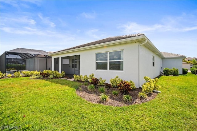 28041 Captiva Shell Loop, Bonita Springs, FL 34135 - back of house with a lawn, stucco siding, and glass enclosure