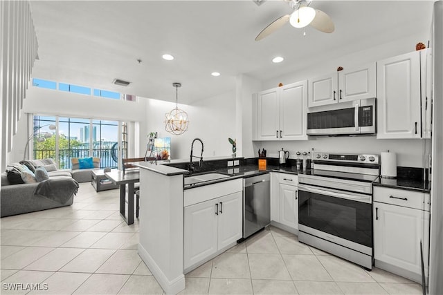 2743 1st St Unit 110, Fort Myers, FL 33916 - kitchen with stainless steel appliances, a sink, a peninsula, open floor plan, and dark countertops