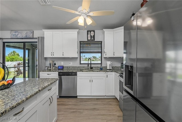 325 NE 24th Ter, Cape Coral, FL 33909 - kitchen with stainless steel appliances, a sink, white cabinets, light wood-type flooring, and a ceiling fan