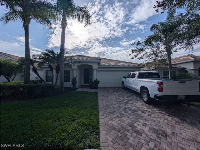 4133 Madison St, Ave Maria, FL 34142 - mediterranean / spanish-style home with a garage, decorative driveway, a tiled roof, stucco siding, and a front yard
