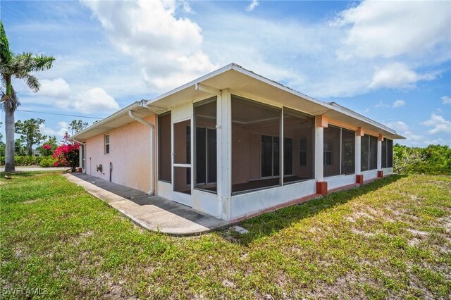 188 Ingram Blvd, Rotonda West, FL 33947 - back of house featuring a sunroom, a yard, and stucco siding