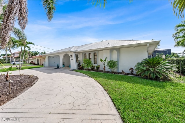 5630 Riverside Dr, Cape Coral, FL 33904 - view of front of home with stucco siding, a garage, a front lawn, driveway, and metal roof