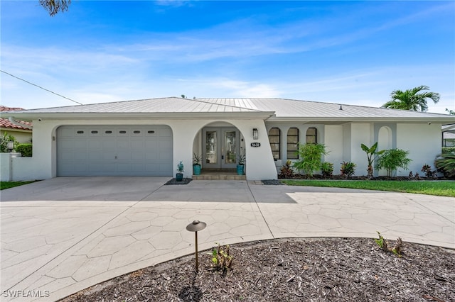 5630 Riverside Dr, Cape Coral, FL 33904 - single story home featuring stucco siding, driveway, french doors, a garage, and metal roof