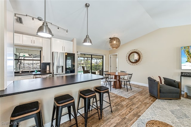 5630 Riverside Dr, Cape Coral, FL 33904 - kitchen featuring stainless steel refrigerator with ice dispenser, dark countertops, lofted ceiling, a sink, and a kitchen bar