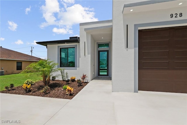 928 NE 8th Place, Cape Coral, FL 33909 - doorway to property featuring stucco siding, an attached garage, and central AC unit