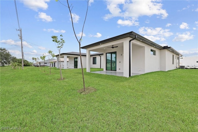 928 NE 8th Place, Cape Coral, FL 33909 - rear view of property with stucco siding, a yard, a ceiling fan, cooling unit, and a patio