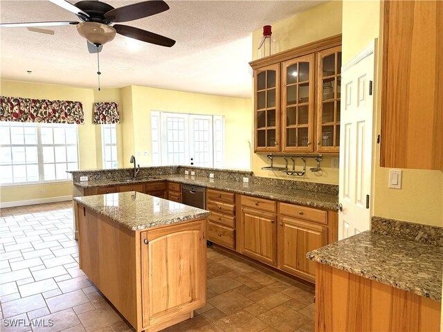 4150 Enclave Pl, Punta Gorda, FL 33980 - kitchen with stainless steel dishwasher, a textured ceiling, a sink, a peninsula, and glass insert cabinets