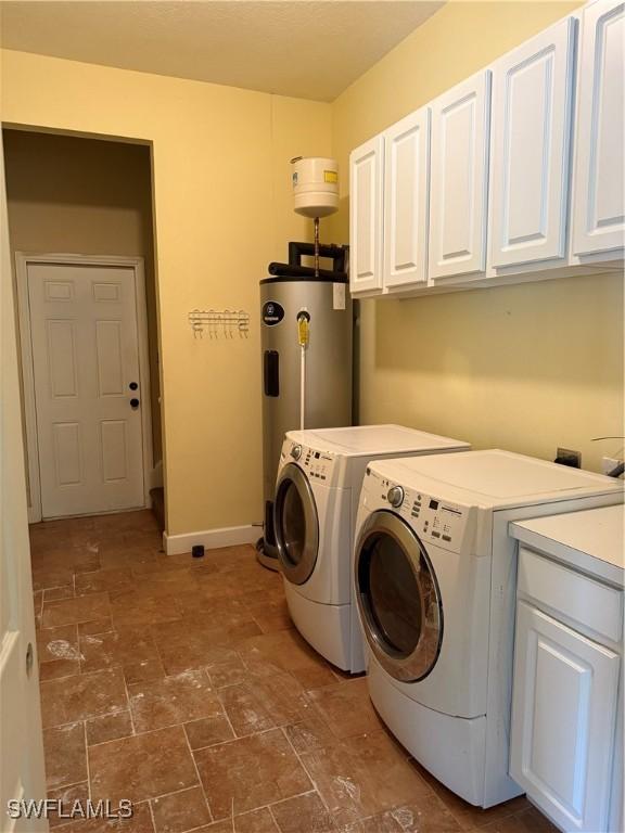 4150 Enclave Pl, Punta Gorda, FL 33980 - laundry room with cabinet space, washing machine and dryer, water heater, dark stone finish flooring, and baseboards