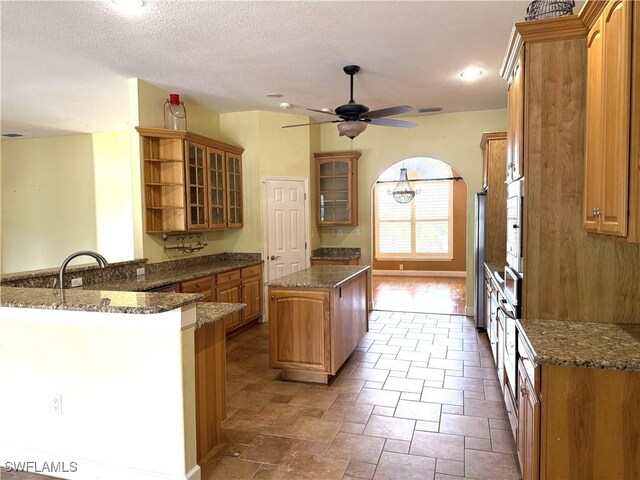 4150 Enclave Pl, Punta Gorda, FL 33980 - kitchen with open shelves, a peninsula, ceiling fan, a center island, and glass insert cabinets