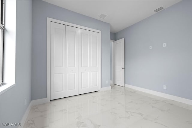 570 Sherwood Ave S, Lehigh Acres, FL 33974 - unfurnished bedroom featuring light marble finish flooring, baseboards, and a closet