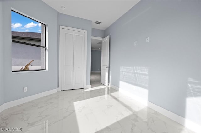 570 Sherwood Ave S, Lehigh Acres, FL 33974 - unfurnished bedroom with marble look tiles, baseboards, and a closet