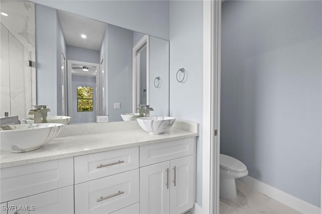 570 Sherwood Ave S, Lehigh Acres, FL 33974 - full bathroom with toilet, double vanity, marble look tiles, and baseboards