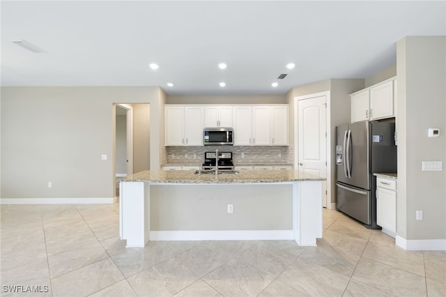 17021 Ashcomb Way, Estero, FL 33928 - kitchen featuring stainless steel appliances, decorative backsplash, white cabinets, a center island with sink, and light stone countertops
