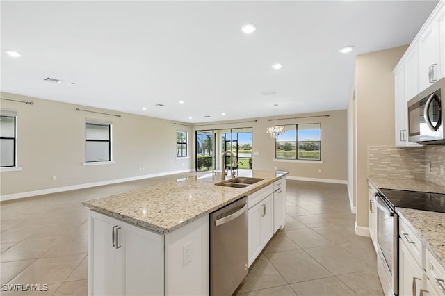 17021 Ashcomb Way, Estero, FL 33928 - kitchen with stainless steel appliances, light tile patterned floors, a center island with sink, decorative backsplash, and recessed lighting