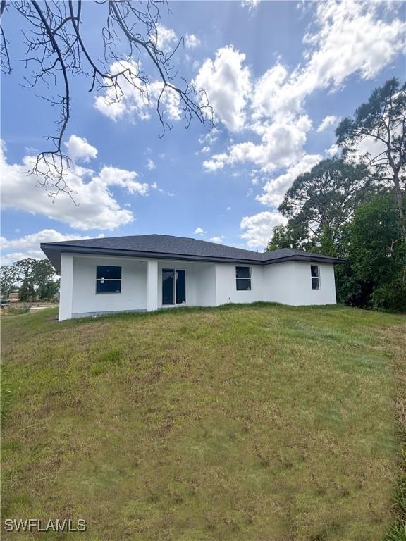 4113 19th St SW, Lehigh Acres, FL 33976 - back of house featuring a yard and stucco siding