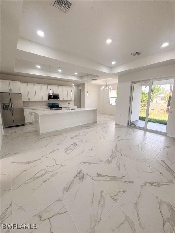 2805 26th St SW, Lehigh Acres, FL 33976 - unfurnished living room featuring a tray ceiling, a chandelier, recessed lighting, and a sink
