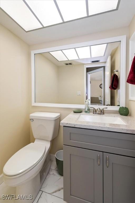 1704 Coral Way N, Fort Myers, FL 33917 - bathroom featuring vanity, toilet, marble finish floors, and baseboards