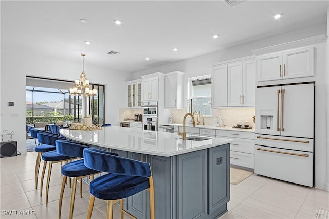 8341 Promoso Ct, Naples, FL 34114 - kitchen with high end white refrigerator, white cabinetry, a kitchen island with sink, light countertops, and tasteful backsplash