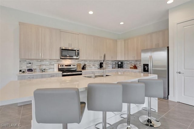 5273 Lamone Ln, Ave Maria, FL 34142 - kitchen with stainless steel appliances, light brown cabinets, a breakfast bar area, light countertops, and recessed lighting