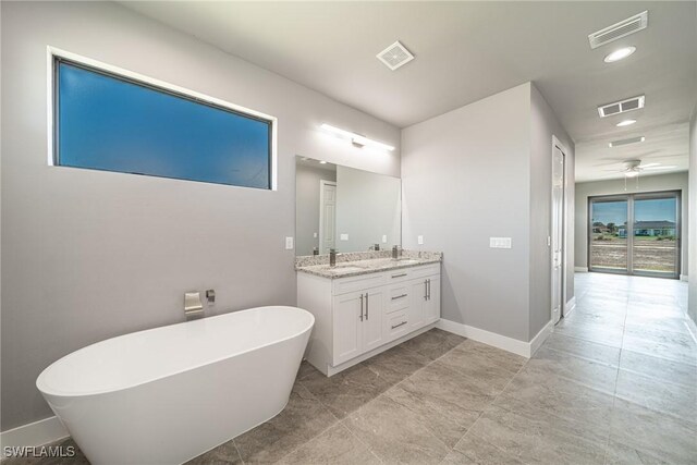 2458 NW 21st Ter, Cape Coral, FL 33993 - bathroom with double vanity, a freestanding tub, a ceiling fan, recessed lighting, and baseboards