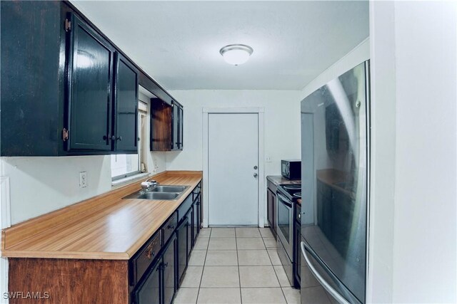 1201 E 15th St, Lehigh Acres, FL 33972 - kitchen featuring a sink, stainless steel range with electric stovetop, black microwave, light tile patterned flooring, and light countertops
