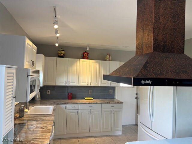 2440 Elkcam Blvd, Port Charlotte, FL 33952 - kitchen with freestanding refrigerator, backsplash, white cabinetry, light tile patterned floors, and rail lighting