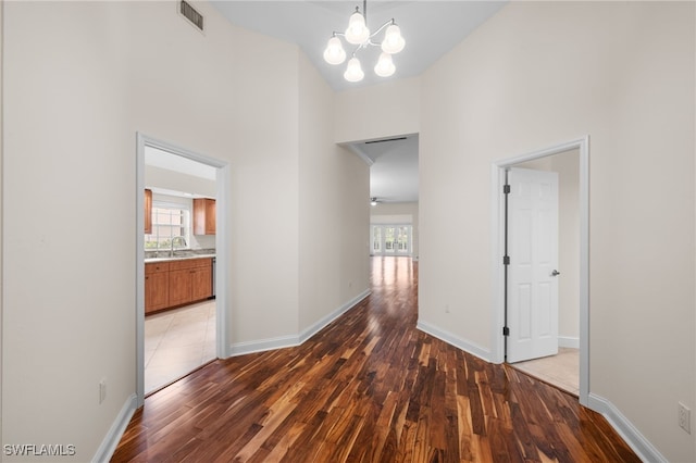 14221 Patty Berg Dr, Fort Myers, FL 33919 - corridor featuring a towering ceiling, a sink, wood finished floors, baseboards, and a chandelier