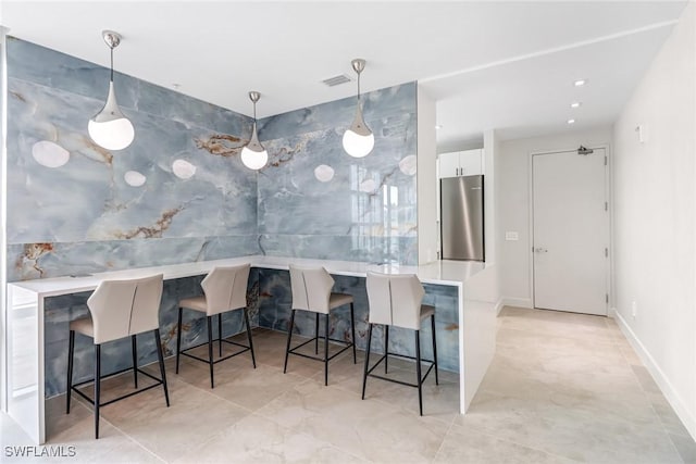 3000 Oasis Grand Blvd Unit 2103, Fort Myers, FL 33916 - kitchen featuring stainless steel refrigerator, white cabinetry, a breakfast bar area, hanging light fixtures, and light countertops