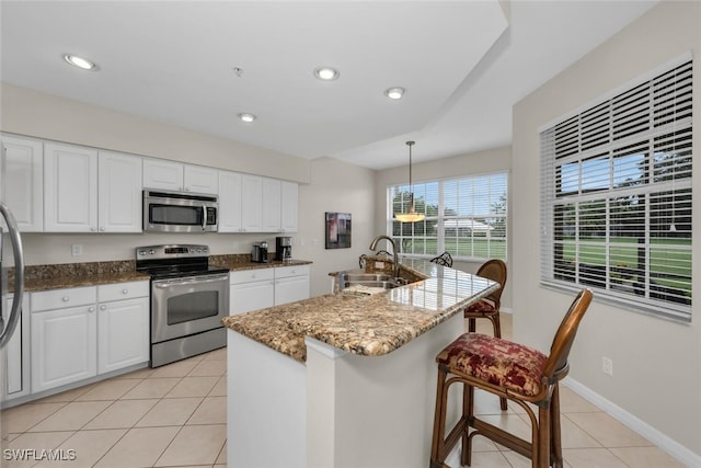 1630 Winding Oaks Way Unit 102, Naples, FL 34109 - kitchen featuring stainless steel appliances, a sink, light tile patterned floors, white cabinets, and a kitchen bar