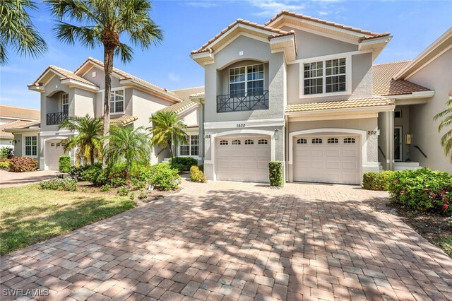 1630 Winding Oaks Way Unit 102, Naples, FL 34109 - view of front of home with an attached garage, decorative driveway, a tiled roof, and stucco siding