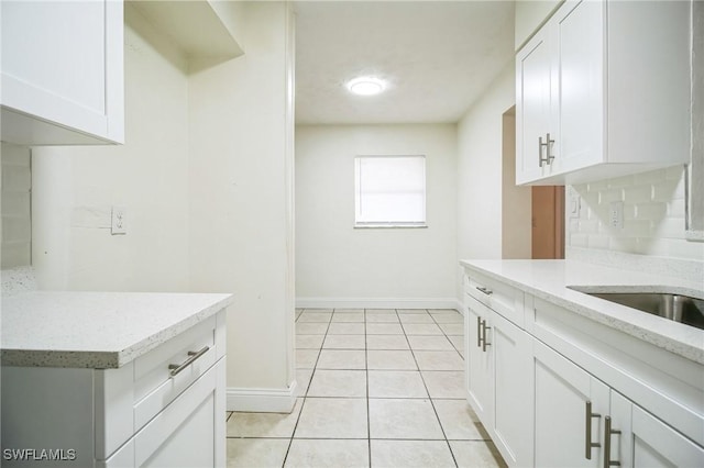 2938 Market St, Fort Myers, FL 33916 - kitchen with baseboards, light stone countertops, white cabinetry, light tile patterned flooring, and decorative backsplash