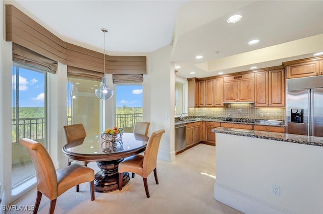 2738 Tiburon Blvd E Unit Ph-B502, Naples, FL 34109 - kitchen featuring appliances with stainless steel finishes, dark stone countertops, brown cabinetry, backsplash, and decorative light fixtures