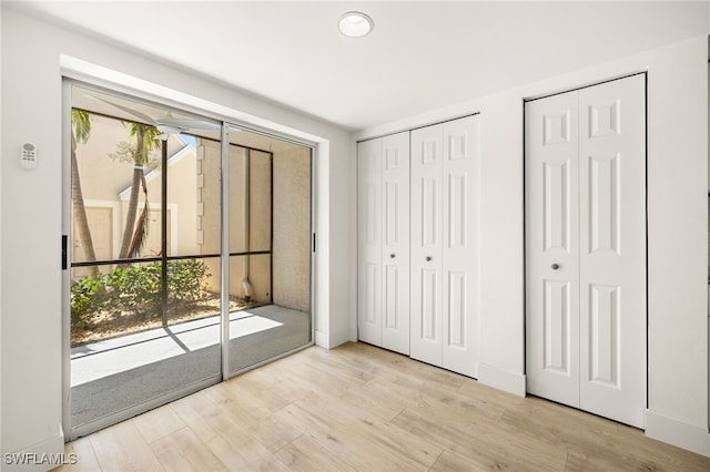 16320 Kelly Cove Dr Unit 270, Fort Myers, FL 33908 - unfurnished bedroom featuring multiple closets, wood finished floors, access to exterior, recessed lighting, and baseboards