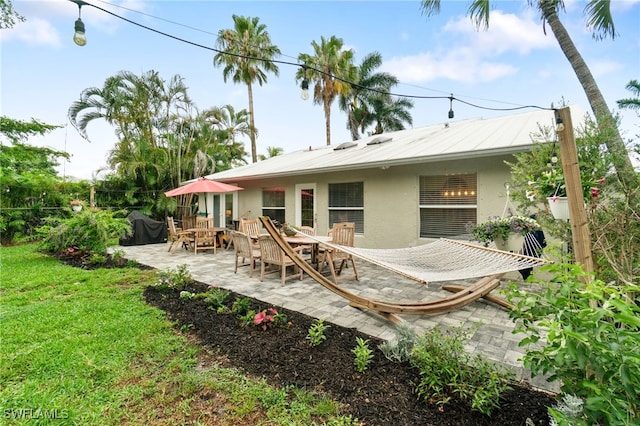 955 Hidden Terrace Rd, Naples, FL 34104 - back of property featuring stucco siding, a patio area, a yard, and outdoor dining space