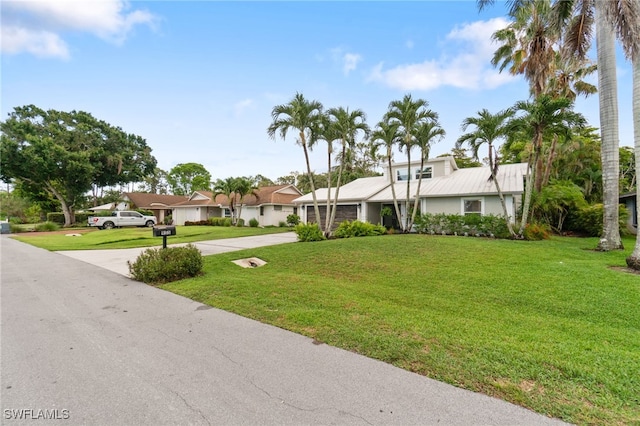 955 Hidden Terrace Rd, Naples, FL 34104 - mid-century modern home with concrete driveway, an attached garage, a front lawn, and a residential view