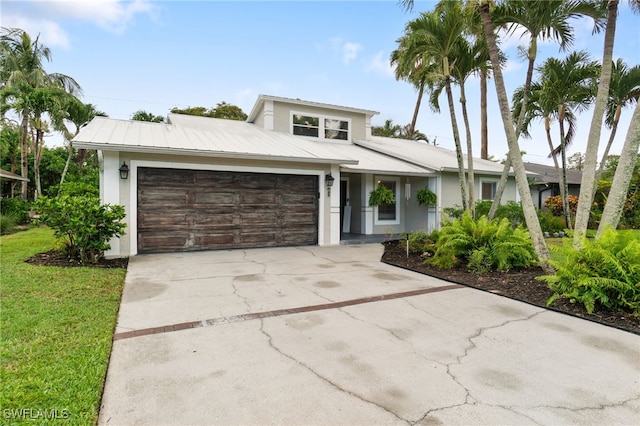 955 Hidden Terrace Rd, Naples, FL 34104 - view of front of property with a garage, driveway, metal roof, stucco siding, and a front yard