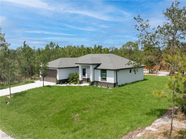 1015 Gerald Ave, Lehigh Acres, FL 33936 - view of front of home featuring a front lawn, an attached garage, concrete driveway, stucco siding, and roof with shingles