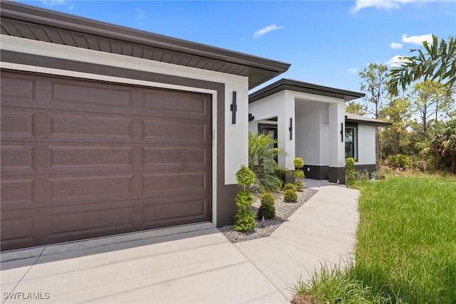 1015 Gerald Ave, Lehigh Acres, FL 33936 - property entrance featuring stucco siding, an attached garage, and concrete driveway