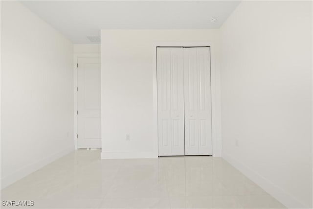 1015 Gerald Ave, Lehigh Acres, FL 33936 - unfurnished bedroom with baseboards, light tile patterned flooring, and a closet