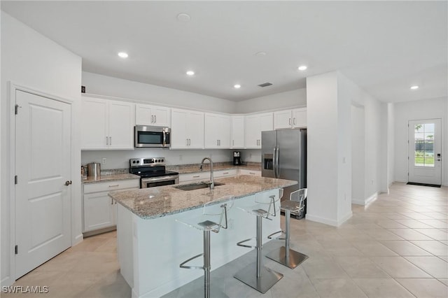 13952 Hunter Oak Dr, Fort Myers, FL 33913 - kitchen featuring stainless steel appliances, a sink, a kitchen island with sink, light stone counters, and white cabinets