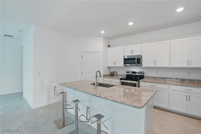13952 Hunter Oak Dr, Fort Myers, FL 33913 - kitchen with stainless steel appliances, a sink, a kitchen island with sink, white cabinetry, and light stone counters