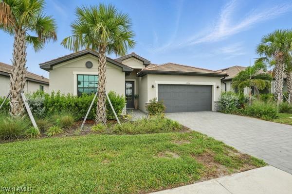 13952 Hunter Oak Dr, Fort Myers, FL 33913 - ranch-style house with stucco siding, an attached garage, decorative driveway, and a front yard