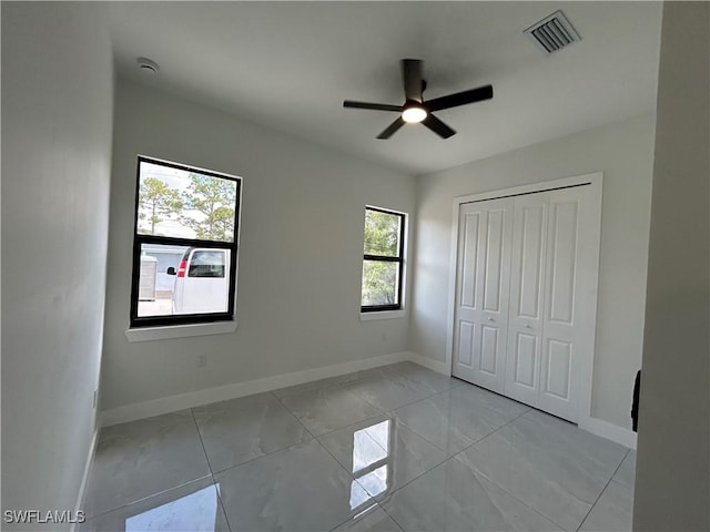 2815 4th St SW, Lehigh Acres, FL 33976 - unfurnished bedroom with light marble finish flooring, baseboards, a closet, and ceiling fan