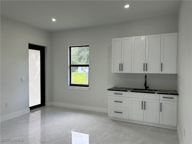 2815 4th St SW, Lehigh Acres, FL 33976 - kitchen with a sink, baseboards, dark countertops, light marble finish flooring, and recessed lighting