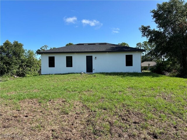 2815 4th St SW, Lehigh Acres, FL 33976 - back of house with stucco siding and a yard