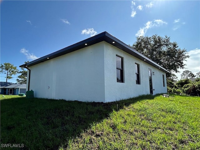 2815 4th St SW, Lehigh Acres, FL 33976 - view of side of home featuring stucco siding and a lawn