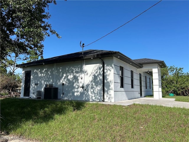 2815 4th St SW, Lehigh Acres, FL 33976 - view of home's exterior featuring cooling unit, a yard, and stucco siding