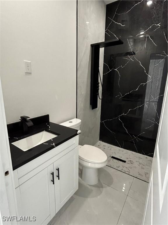 2815 4th St SW, Lehigh Acres, FL 33976 - bathroom featuring vanity, a marble finish shower, toilet, and marble look tiles