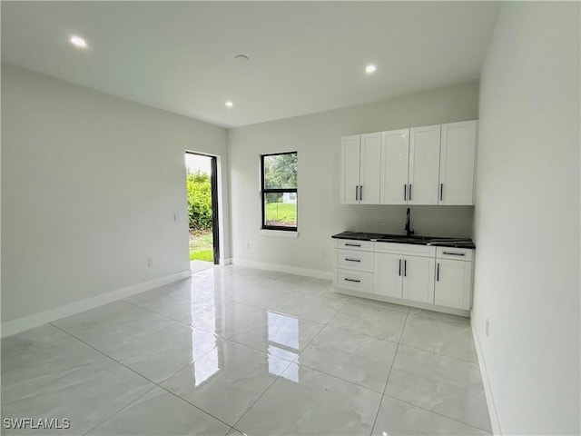 2815 4th St SW, Lehigh Acres, FL 33976 - kitchen with a sink, baseboards, recessed lighting, dark countertops, and white cabinetry