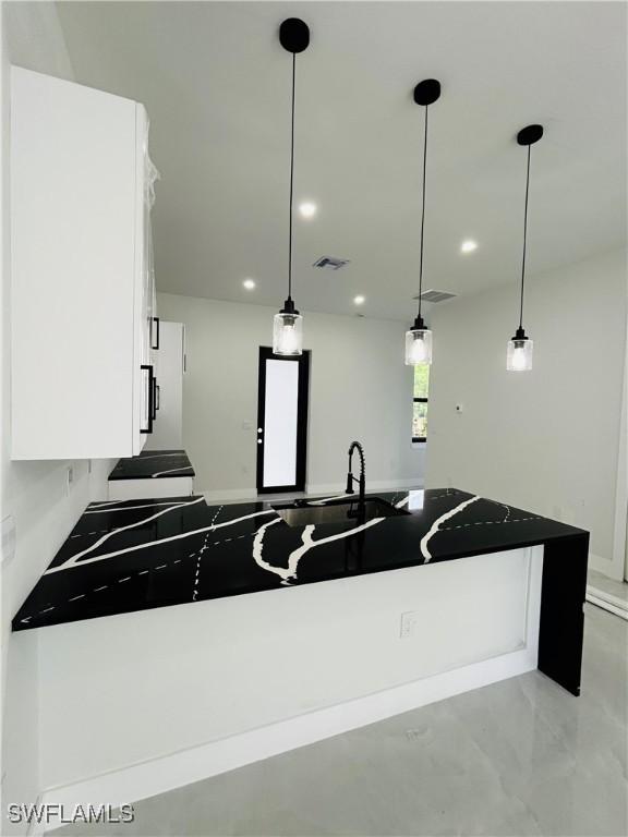 2815 4th St SW, Lehigh Acres, FL 33976 - kitchen with white cabinetry, recessed lighting, pendant lighting, dark countertops, and a sink